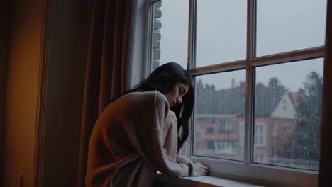 woman sitting by the window on a rainy day