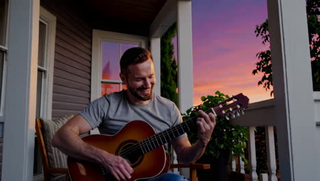 man playing guitar on a porch at sunset