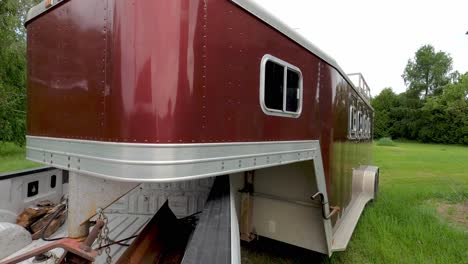 pulling colorful horse trailer out of private farmstead, back view