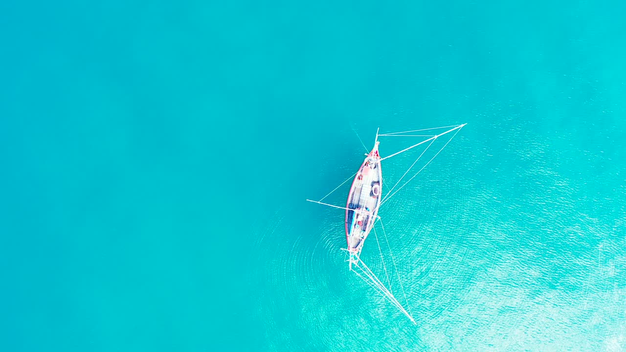 barco de pesca con redes colgantes sobre aguas tranquilas y claras de la laguna turquesa que refleja los rayos del sol en la hermosa bahía de fiji