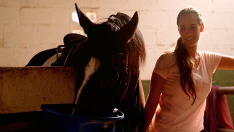 mujer de pie con el caballo en el establo 4k