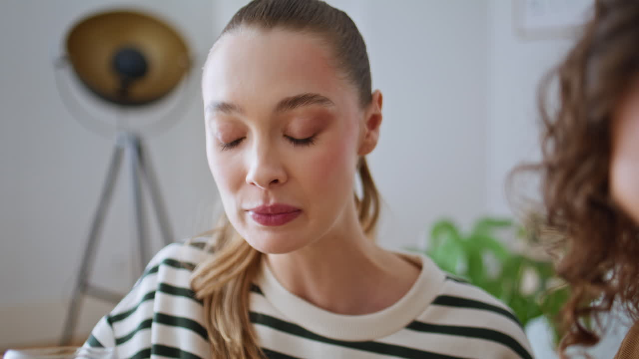 Woman drinking fresh orange juice in home kitchen breakfasting with man closeup