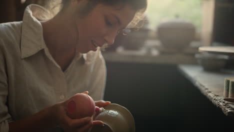 excited lady doing handicraft on clay product in pottery. woman drawing ornament