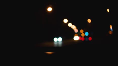el tráfico borroso de la ciudad en la calle de la ciudad. los semáforos nocturnos desenfocados. la vista desde la ventana del coche a la carretera de la ciudad nocturna.