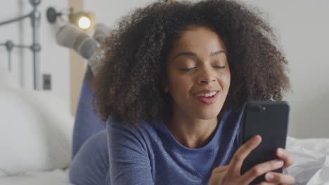 Mujer-Con-Teléfono-Móvil-En-Pijama-Teniendo-Video-Chat-Acostada-En-La-Cama