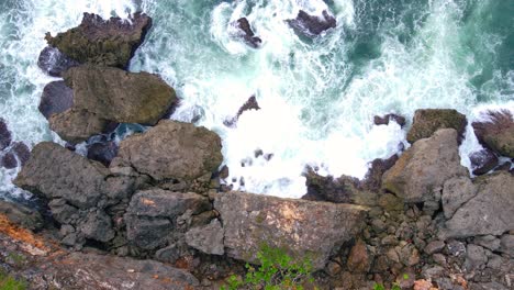 Overhead-drone-shot-of-big-sea-wave-hits-the-big-rocks-on-the-beach