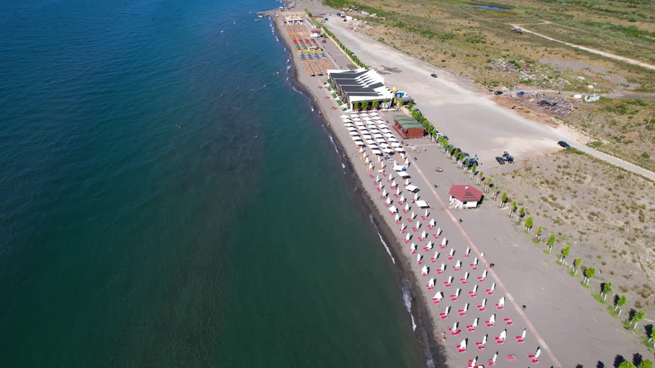 Flight over a bathing beach with parasols in Albania near Velipoja