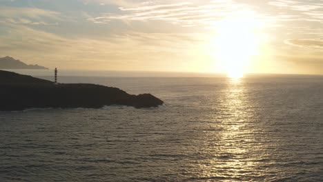 Panorama-drone-shot-of-a-lighthouse-at-golden-hour-with-sun-and-ocean