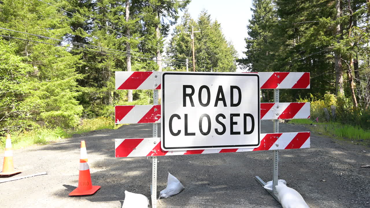 Road Closed Sign on a residential street lines with trees. Roadsign blocking through traffic.