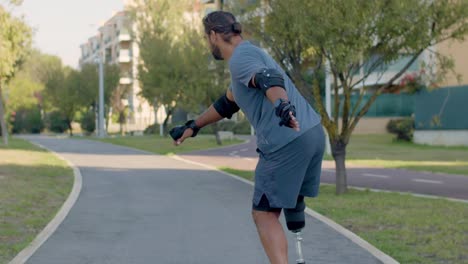vista trasera de un hombre con una pierna protésica montando en patineta