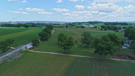 Eine-Luftaufnahme-Der-Farmlandschaft-Mit-Bepflanzten-Feldern-Und-Einer-Einzigen-Eisenbahnstrecke-In-Einer-Kurve-An-Einem-Schönen-Sonnigen-Tag