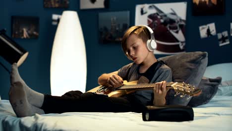 boy in headphones learning song with guitar