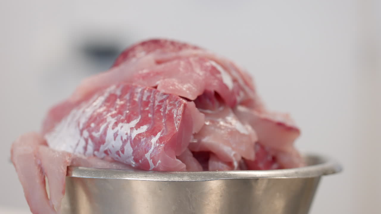 carne de pescado de arenque fresco y sin cocinar en un cuenco de acero inoxidable.