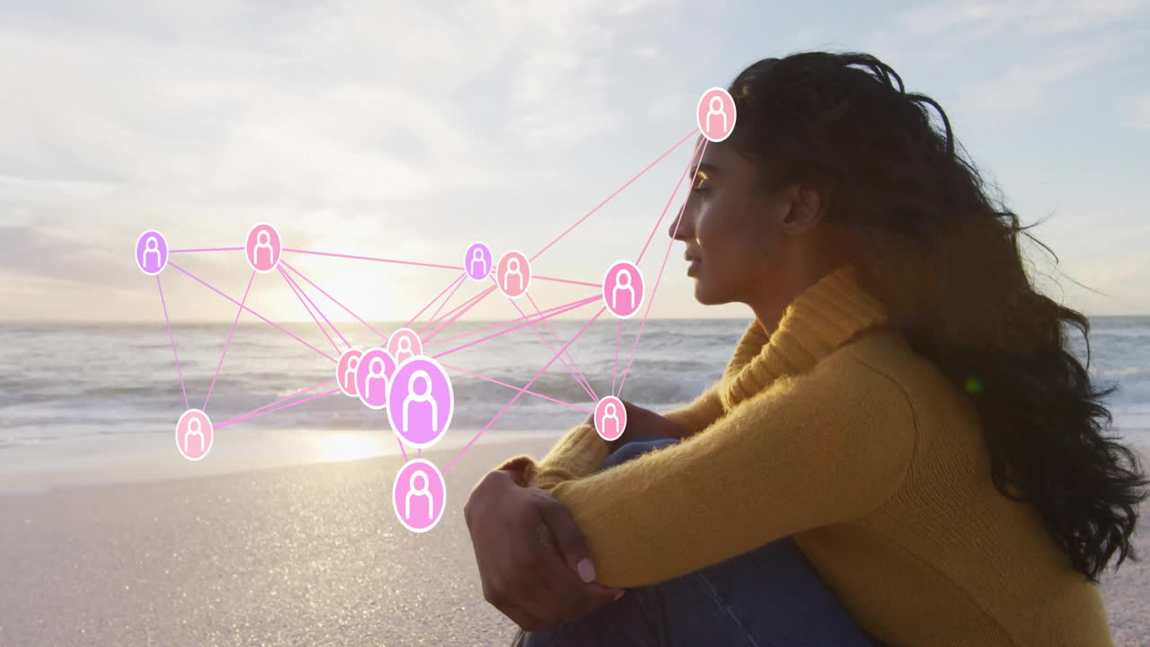 Woman sitting on beach at sunset, showcasing technology network with floating user icons over ocean
