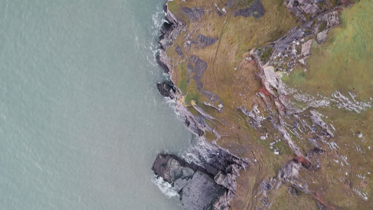 aéreo: vuelo de arriba hacia abajo a lo largo de acantilados costeros cubiertos de hierba, rhossili gower, dron 4k