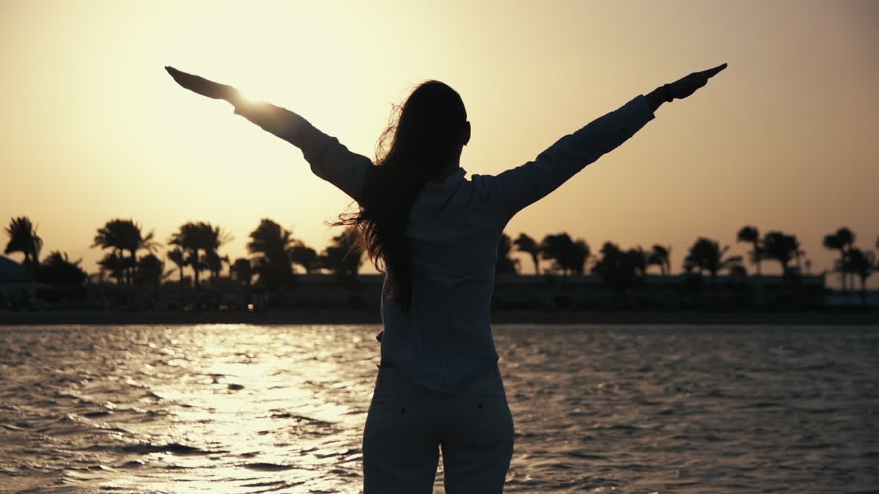 hermosa mujer disfrutando de la puesta de sol con los brazos abiertos. niña descansando en la costa