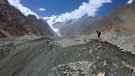 Wide-drone-shot-passing-by-person-hiking-up-a-mountain-ridge-in-Passu-Cones-Pakistan,-cinematic-wide-revealing-aerial-shot