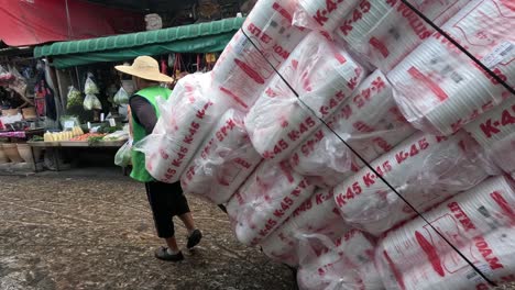 worker transports large bags through busy market