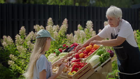 A-girl-and-her-grandmother-lay-out-vegetables-at-a-farmer's-market-counter