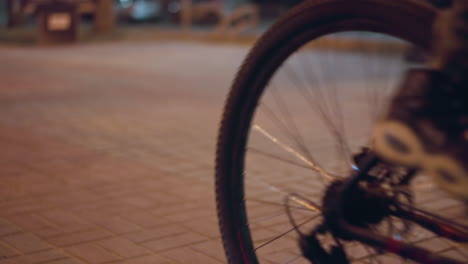 close view of cyclists riding on a city street at night capturing the motion with a focus on the cyclists' wheels and the illuminated pavement