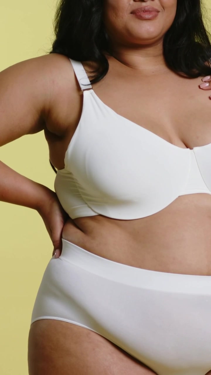 Video verticale: Panoramica della telecamera su una modella che sistema gli slip e aggiusta il reggiseno con ferretto, mostrando la vestibilità in studio
