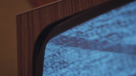 close up of ancient and old wooden television station screen with no tv signal, emitting flickering light in the attic in slowmo
