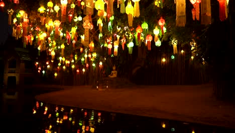 estatua dorada de buda debajo de un árbol decorado con lámparas de papel de colores en el templo de chiang mai, tailandia