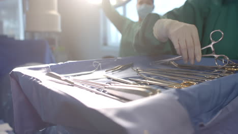 midsection of female surgeon preparing surgical instruments in operating theatre, slow motion