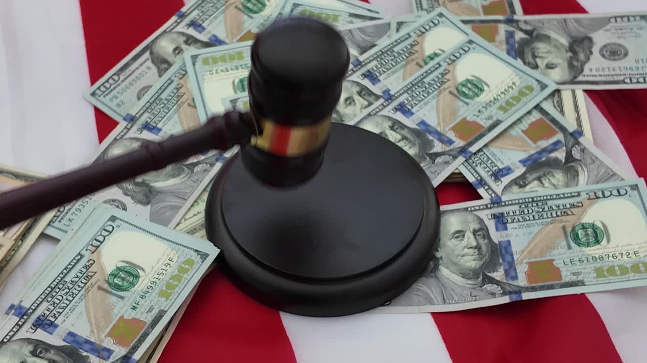 A gavel, once a symbol of authority and lawful order, now lies wrapped in scattered bills and shadowed by the weight of money. The judicial hammer that should strike with fairness