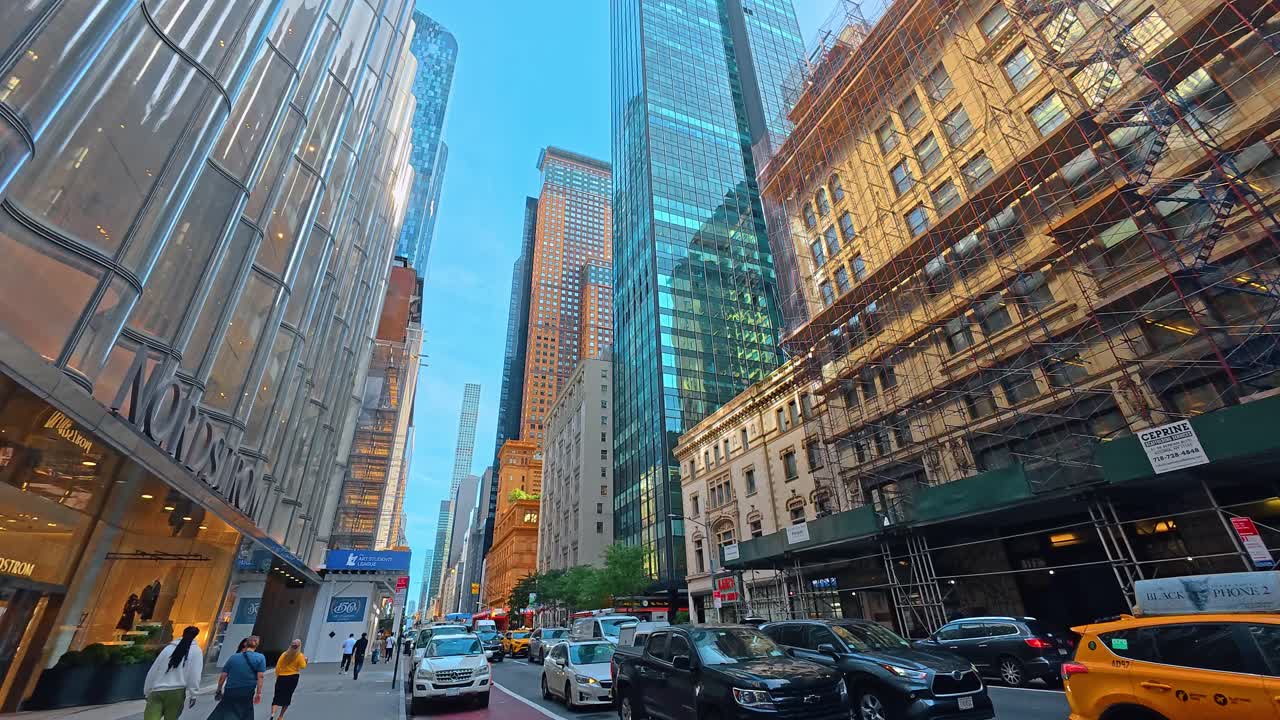 New York, USA, 5 agosto 2025: Scena di strada trafficata con pedoni e auto a New York. Scena di strada urbana a New York City con pedoni, traffico e grattacieli di vetro sotto un cielo azzurro.