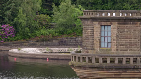 shot of the dam control building with a bellmouth overflow in background at ladybower reservoir taken from the dam.
