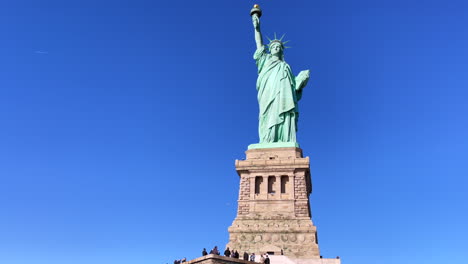 tourists enjoy the view of the tall statue of liberty in new york city on a sunny day