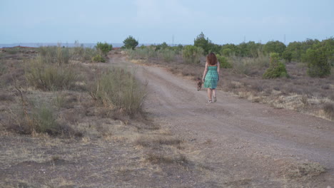 woman walking with her dog on a dirt road