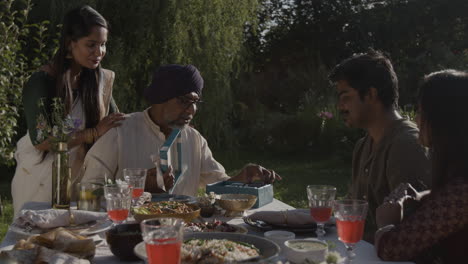 multi-generational indian family gathering outdoors for a meal and celebration