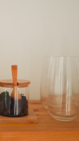 estante con artículos de cocina en la habitación. artículos para el hogar y almacenamiento de comestibles en frascos de vidrio en mesa de madera. elementos interiores en premisas ligeras