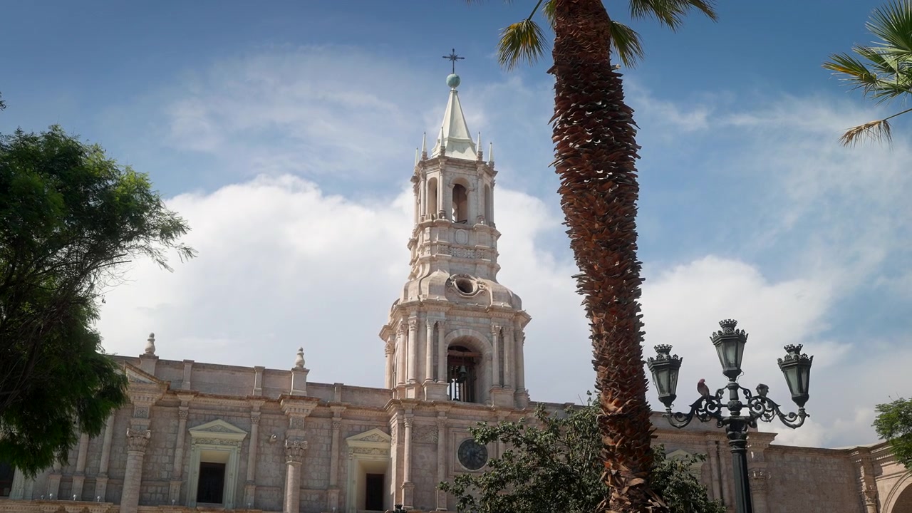 Vista de la catedral en la Plaza de Armas de Arequipa, Perú, con arquitectura colonial, palmeras y la histórica plaza central de la ciudad.
