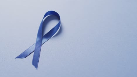video of dark blue colon cancer ribbon on pale blue background