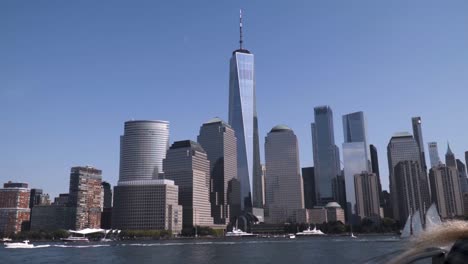 financial district on manhattan in new york city in slow motion from water. one world trade center in the middle during noon and sunny weather with no clouds.