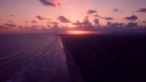 Drone-shot-of-pink-sky-sunset-over-the-ocean-beach-with-waves-in-Brazil