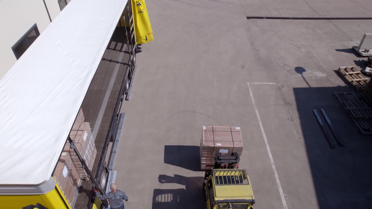 Forklift loading a truck with wooden pallets