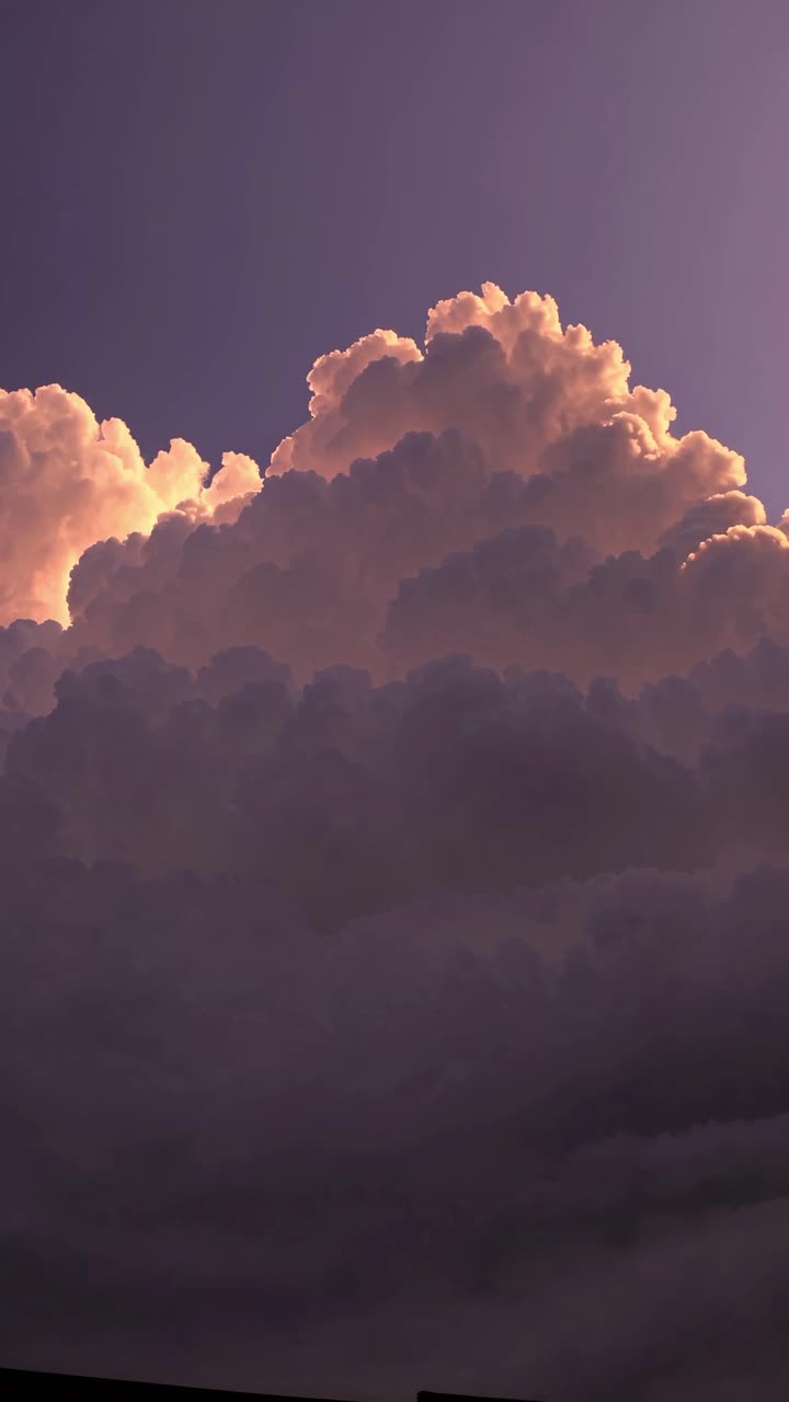 A dramatic video still of towering clouds at sunset, captured from a low angle