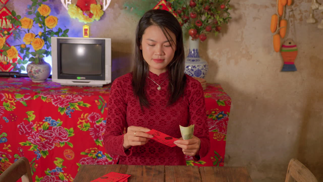 Chinese New Year celebration woman wearing red dress preparing envelope with money