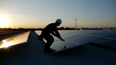 worker inspecting solar panels at sunset