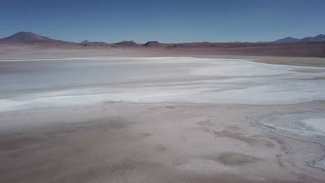 Bolivia's-captivating-landscape,-aerial-of-vast-white-salt-surface-desert-that-extends-to-the-distant-horizons