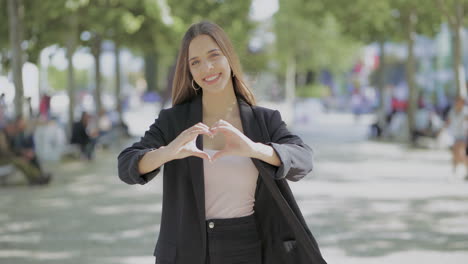 chica feliz atractiva mostrando la mano el corazón