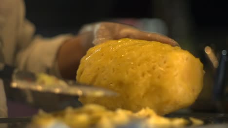 freshly peeled yellow pineapple being removed of husk by small knife, filmed in slow motion as close up