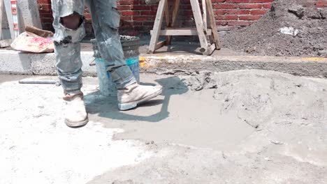 worker pouring fresh cement onto pavement at a sunny outdoor construction site