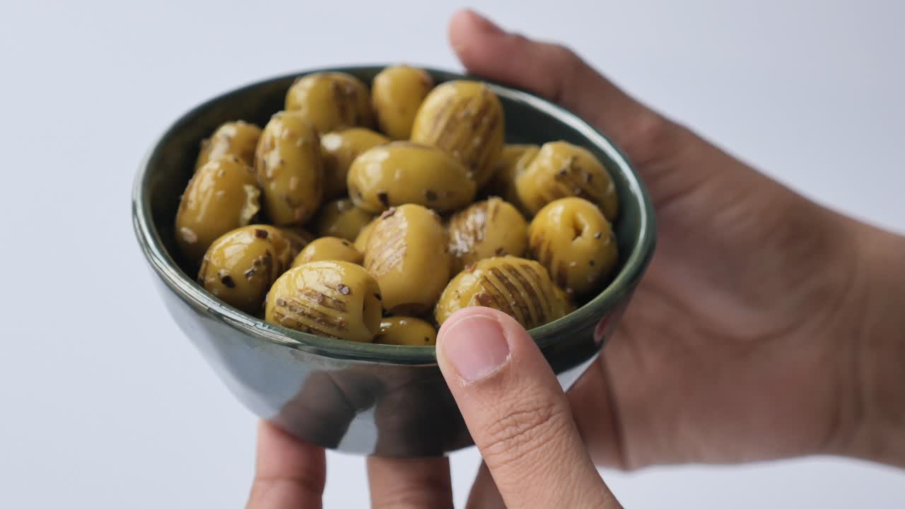 mano con un cuenco de aceitunas verdes