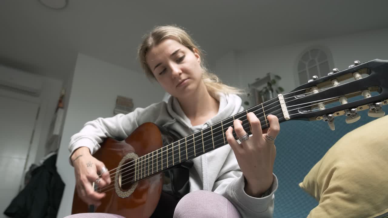 Young woman enjoying a creative moment while playing acoustic guitar at home