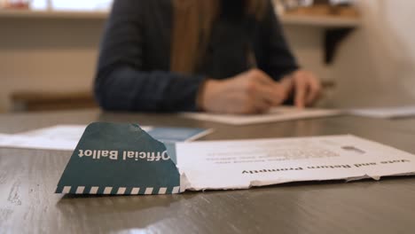 view of an official ballot sleeve in focus with someone voting in the background